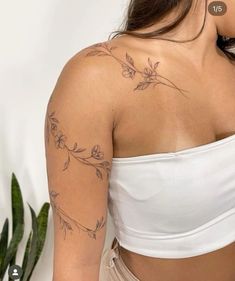 a woman with a tattoo on her arm and shoulder is looking down at the ground