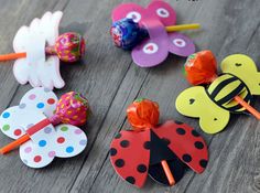 colorful paper flowers and ladybug pinwheels on a wooden table