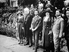 a group of people standing next to each other in front of a fence and bushes