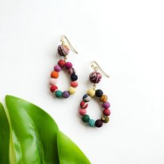 A teardrop of twelve colorful Kantha beads dangle from a larger center bead to create a lightweight, statement-making drop earring. Made from repurposed Kantha textiles; colors and patterns of the beads will vary. Finished with nickel-free and lead-free French earring wires. Sustainably handmade by women artisans in India. Details: Measures 2" long. Printed Candles, Free In French, Earring Wires, Puzzles Gifts, Branded Gifts, Dangling Earrings, Drop Earring, Women Artisans, Beaded Dangles