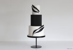 a three tiered cake with black and white designs on it's sides, sitting on a stand