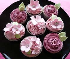 cupcakes with pink frosting and flowers on a black plate