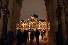 people are walking through an archway at night