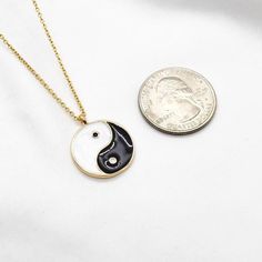 two pieces of jewelry sitting next to each other on a white surface with a coin in the background