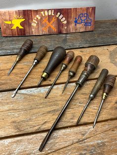 seven woodworking tools are lined up on a wooden table next to a sign that says,