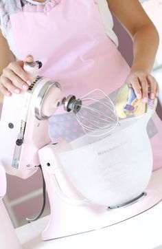 a woman in an apron is using a mixer