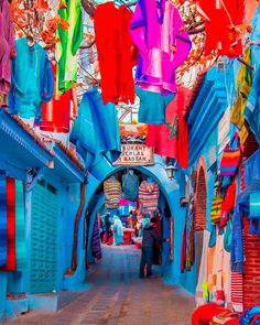 an alley way with colorful clothes hanging from the ceiling