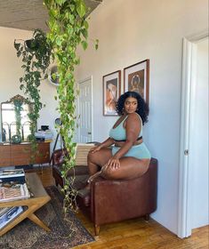 a woman sitting on a couch in a living room next to a potted plant