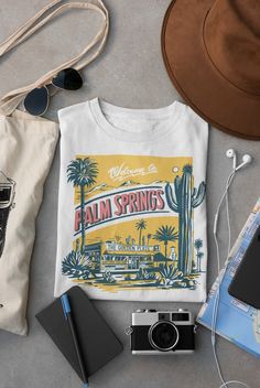 A perfect blend of nostalgia and style that takes you back in time to the golden era of the 1950s. This t-shirt is inspired by the iconic landmarks of Palm Springs, featuring cacti, mountains, and the legendary diner, The Golden Plate. The t-shirt design showcases the breathtaking beauty of Palm Springs with its unique combination of desert landscape and towering mountains. The image of the cacti brings to life the rugged terrain of the desert, while the mountain range adds a touch of majesty an Nashville Fits, Palm Springs Retro, Golden Plate, Retro Diner, Breathtaking Beauty, Desert Landscape, Style T Shirt, Iconic Landmarks, Western Outfits