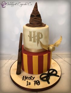 a harry potter birthday cake with hogwart's hat and wands on top