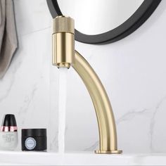 a faucet that is connected to a sink in a bathroom with black and gold accessories