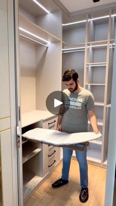 a man standing in front of a closet holding an ironing board on top of it