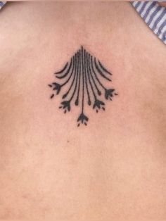 the back of a woman's neck with an intricate tattoo design on her chest