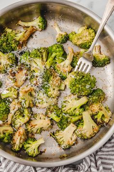 broccoli florets are being cooked in a skillet with a fork