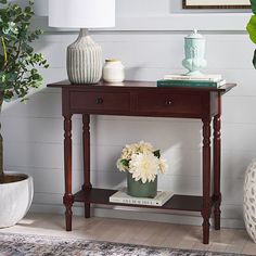 a wooden table with flowers on it and a white lamp next to it in a living room