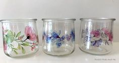 three glass jars with painted flowers on them