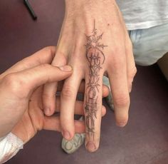 two people holding hands with tattoos on their fingers and the other hand is pointing at them