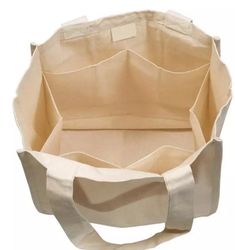 an open canvas bag with handles and straps on the bottom, sitting in front of a white background