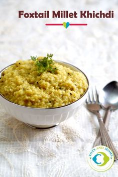 a white bowl filled with food on top of a table next to two silver spoons