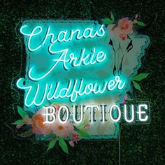 a neon sign with flowers on it that says chaas arlie wildflower boutique