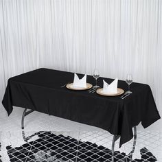 two empty glasses are sitting on a black tablecloth with white plates and napkins