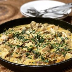 a pan filled with food sitting on top of a table next to a fork and knife