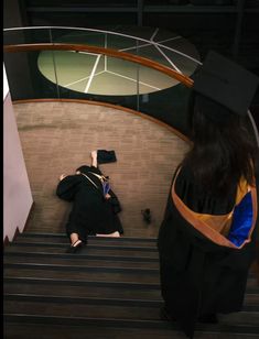 a person laying on the ground in front of some stairs wearing a graduation cap and gown