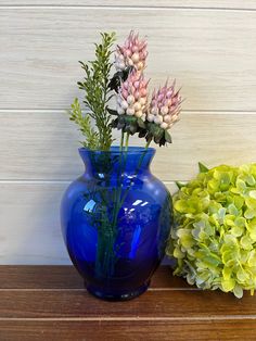 two blue vases with flowers in them sitting on a table next to each other