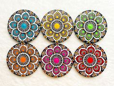 six colorful coasters with designs on them sitting on top of a white surface in the shape of a flower