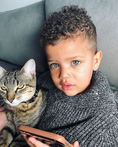 a little boy that is sitting next to a cat