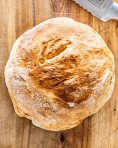 a loaf of bread sitting on top of a wooden cutting board next to a knife