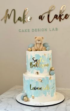 a blue and white cake with a teddy bear on top