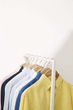 a rack with shirts hanging on it in front of a wall and a white background