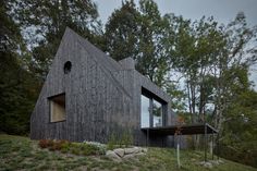 a wooden house sitting on top of a hill next to some trees in the forest