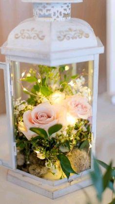 a white lantern with pink roses and greenery