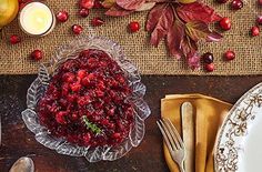 the table is set with plates, silverware and other holiday decorating items including pomegranates