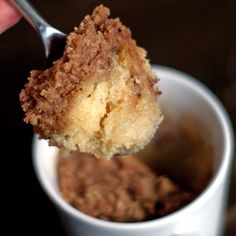 a close up of a person holding a spoon in a cup with food on it