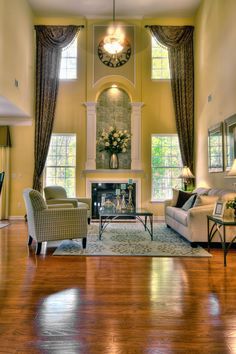 a living room with two couches, chairs and a fire place in the center