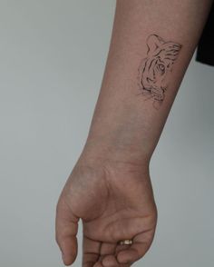 a hand with a small tiger tattoo on it's left wrist and the other arm