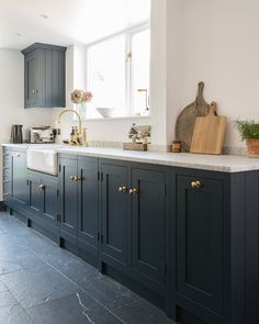 a kitchen with black cabinets and gold handles on the faucet above the sink