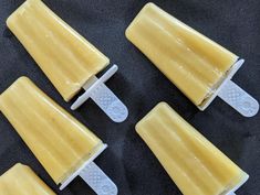 four pieces of yellow ice cream sitting on top of a black countertop next to each other