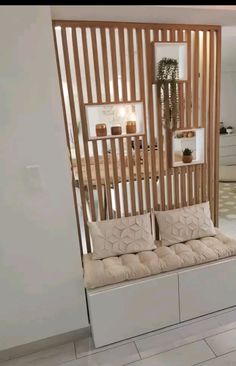 a room divider made out of wooden slats with pillows on the seat area