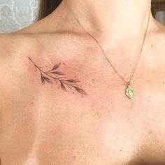 a woman's chest with a small tattoo design on the left side of her neck