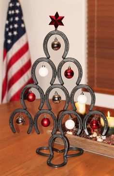 a christmas tree made out of horseshoes and ornaments on a table with an american flag in the background