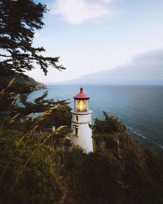 a light house sitting on top of a hill next to the ocean