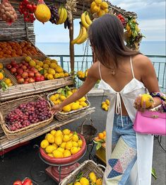 a woman standing in front of a fruit stand