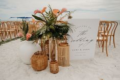 there is a sign and some vases on the beach with flowers in each one