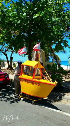 a man standing next to a yellow boat on the street