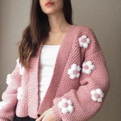 a woman wearing a pink cardigan with white flowers on it