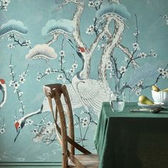 the wallpaper in this dining room is painted with birds and flowers, while two chairs are